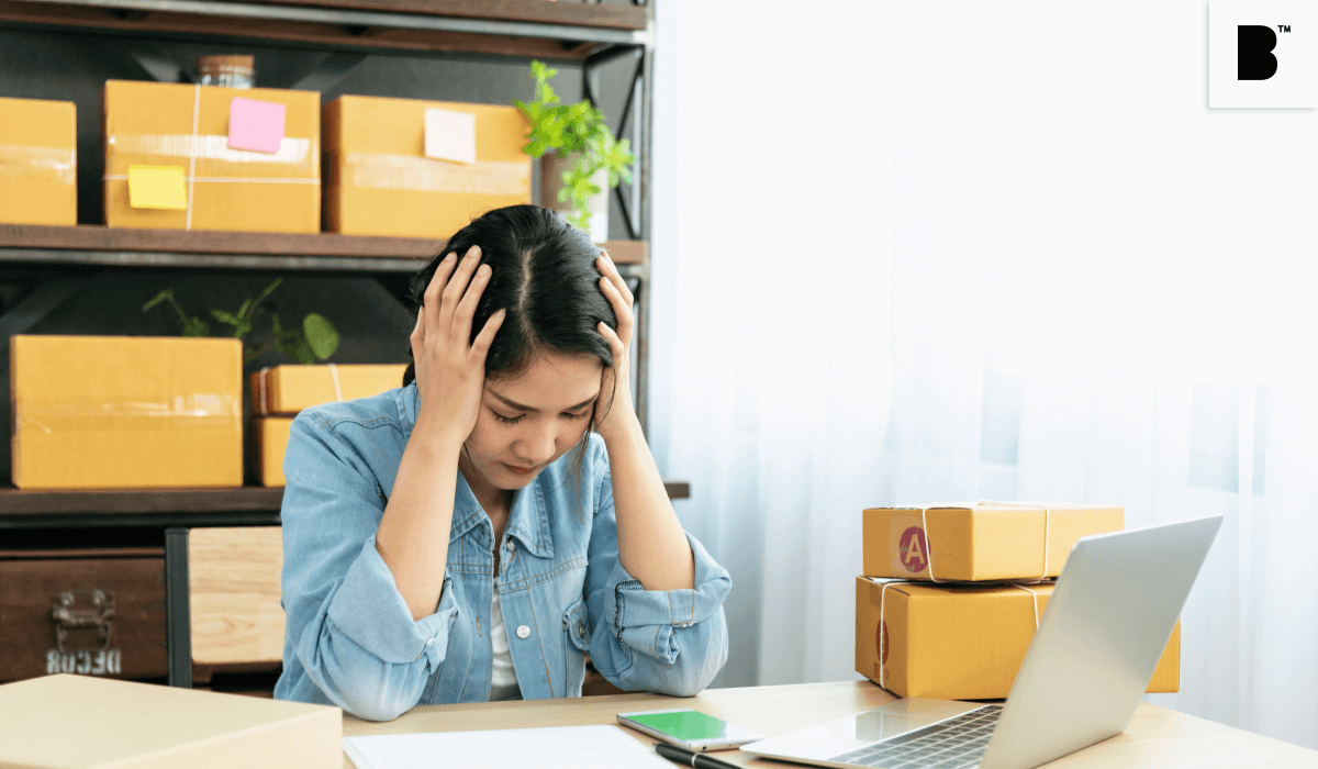  A depressed Commerce retailer sitting in front of her laptop with delivery boxes