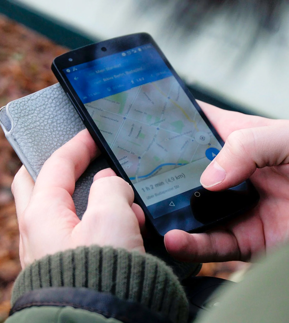 Hands holding a phone highlighting a map where the user is searching for a navigation route